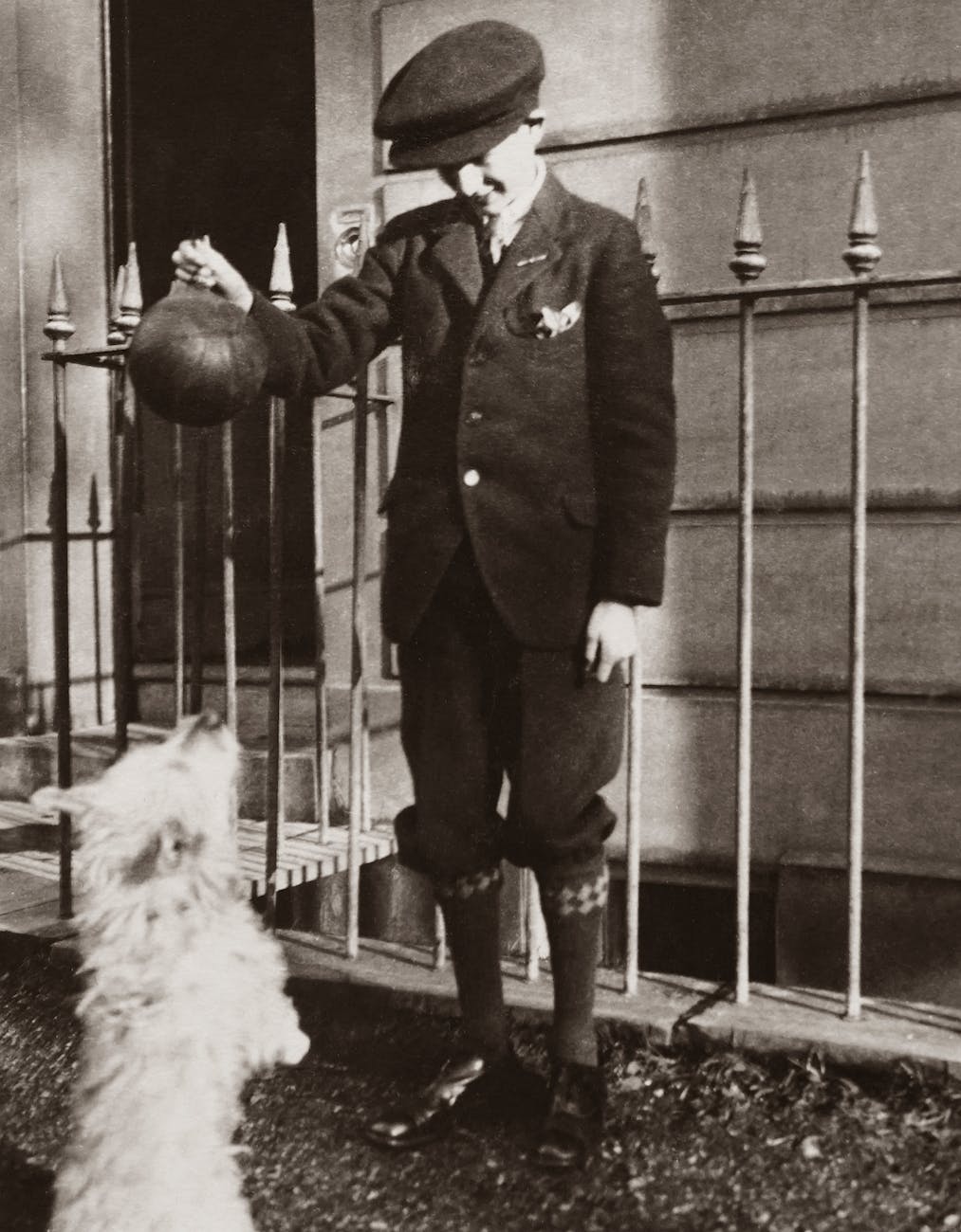 old photograph of a well-dressed child playing with his pet dog